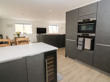 An open kitchen and living area with grey cabinets and a dining table with chairs at 3 Praa Cove in Praa Sands