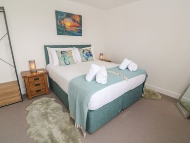 A bedroom with a double bed with two bedside tables and lamps and a wall picture at 3 Praa Cove in Praa Sands