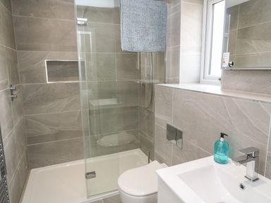A bathroom with a shower area glass partition toilet and a sink with soap dispenser at 3 Praa Cove in Praa Sands