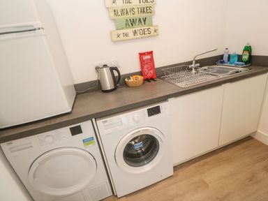 A laundry room with a washing machine dryer refrigerator kettle sink and countertop at 3 Praa Cove in Praa Sands