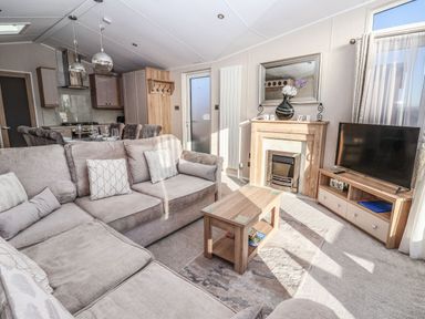 A living room with a beige sofa coffee table fireplace and television in Owl's Nest Newton on Derwent near Wilberfoss