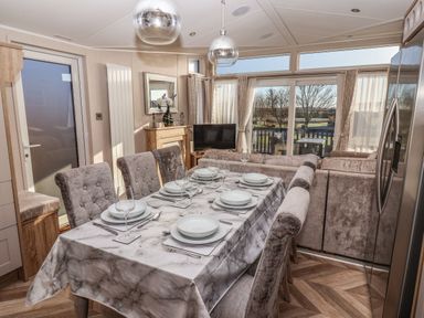 A dining area with a set table next to a living room with sofas and a TV at Owl's Nest in Newton on Derwent near Wilberfoss