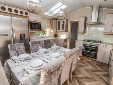 A kitchen with a dining table set for six people stainless steel appliances and wooden cabinets at Owls Nest in Newton on Derwent near Wilberfoss