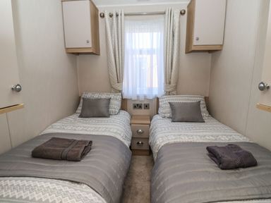 A bedroom with two single beds a nightstand window and wall cabinets at Owls Nest in Newton on Derwent near Wilberfoss
