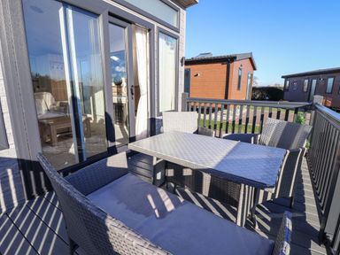 An outdoor deck with a rectangular table and four wicker chairs at Owl's Nest in Newton on Derwent near Wilberfoss