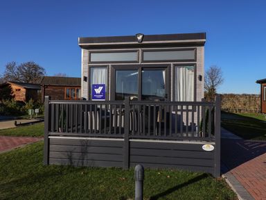 A small gray modular building with a fenced porch and glass doors on a grassy lawn at Owl's Nest Newton on Derwent near Wilberfoss