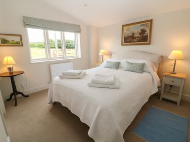 A bedroom with a bed table lamps and paintings at Flagstone Cottage Upper Swell near Stow-On-The-Wold