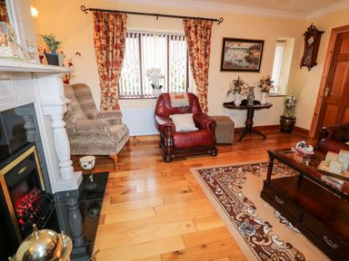 A living room with a fireplace armchairs a coffee table and floral curtains at Derriens Farmhouse Letterbreen County Fermanagh