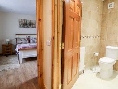A bedroom with a bed and bedside table next to a bathroom with a toilet at Derriens Farmhouse in Letterbreen County Fermanagh