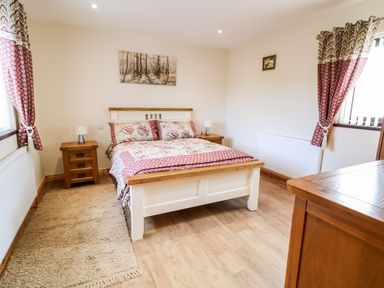 A bedroom with a bed and wooden furniture at Derriens Farmhouse in Letterbreen County Fermanagh