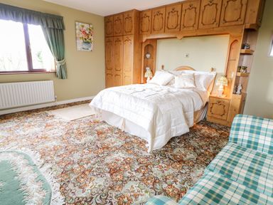 A bedroom with a double bed and wooden built-in wardrobes at Derriens Farmhouse Letterbreen County Fermanagh