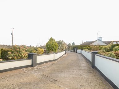 A driveway with low walls and plants on both sides leading to a house at Derriens Farmhouse in Letterbreen County Fermanagh
