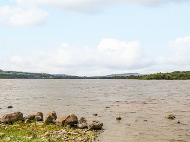 A lake with rocks on the shore and hills in the background at Derriens Farmhouse in Letterbreen County Fermanagh
