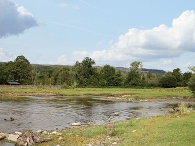 A river with a rocky bank and grassy area with trees and hills in the background at Derriens Farmhouse Letterbreen County Fermanagh