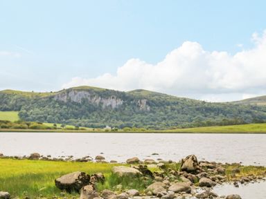 A lake with rocks along the shore and green hills in the background at Derriens Farmhouse Letterbreen County Fermanagh