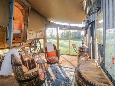 An outdoor seating area with two wooden chairs and a table beside a rustic wagon at The Wagon at Burrow Hill in Ottery St Mary