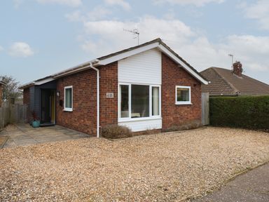 A single-story brick house with a gravel driveway and small bushes at The Lobster Pot in Overstrand
