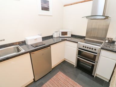 A kitchen with a sink refrigerator toaster microwave and oven at Godolphin Barn in Ashton near Rosudgeon