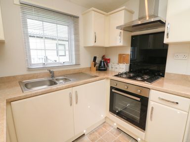 A kitchen with a sink a gas stove an oven and storage cabinets at The Bobbin Number 11 South Lakeland Leisure Village near Carnforth