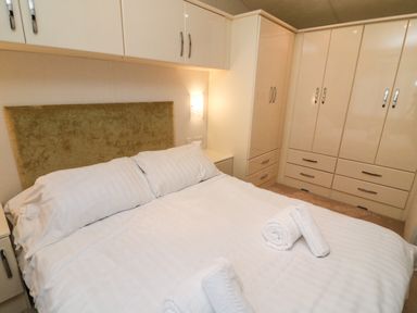 A bedroom with a double bed white linens rolled towels bedside cabinets and built in wardrobes at The Bobbin Number 11 South Lakeland Leisure Village near Carnforth