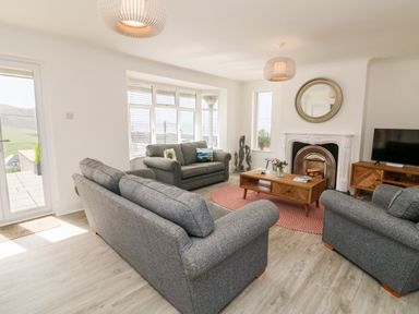 A living room with grey sofas a coffee table a fireplace and a television at Greenbank in Woolacombe