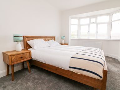 A bedroom with a wooden bed with white bedding and two wooden bedside tables with lamps at Greenbank in Woolacombe