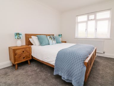 A bedroom with a wooden bed and bedside tables with blue pillows and lamps at Greenbank in Woolacombe