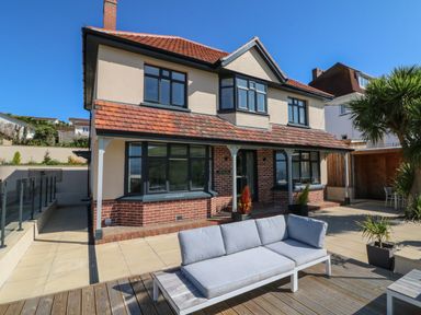 A two story house with a patio sofa and plants outside at Greenbank in Woolacombe