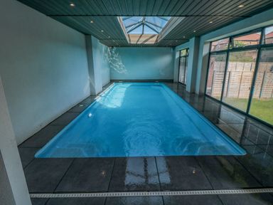 An indoor swimming pool with glass ceiling panels and large windows at Nightingales in Bridlington