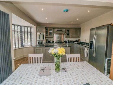 A kitchen with gray cabinets stainless steel appliances and a dining table with flowers at Nightingales in Bridlington