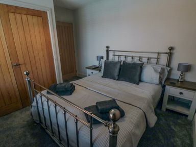 A bedroom with a metal bed frame bed bedside tables and wooden doors at Nightingales Bridlington