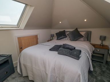 A bedroom with a double bed pillows towels bedside tables lamps and a skylight window at Nightingales Bridlington