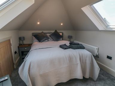A bedroom with a double bed two bedside tables each with a lamp folded towels on the bed and two skylight windows at Nightingales in Bridlington