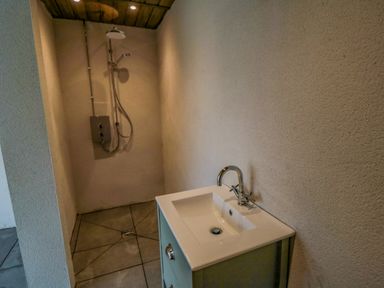 A bathroom with a shower head and a white sink with a faucet at Nightingales in Bridlington