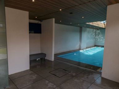 An indoor swimming pool with tiled floor and a bench under a television screen at Nightingales Bridlington