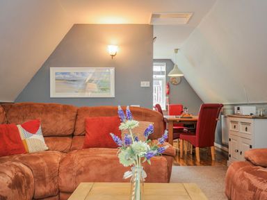 A living room with a sofa and dining area at Hideaway Cottage in St Ann's Chapel, Cornwall