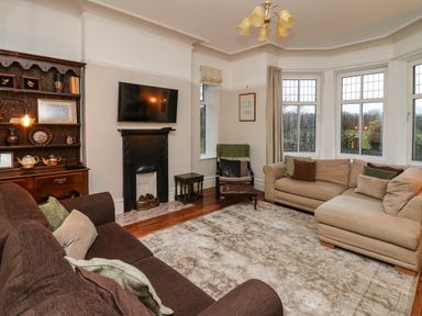 A living room with two sofas a black fireplace a wall-mounted tv and wooden cabinet at Tirallen in Llangadog