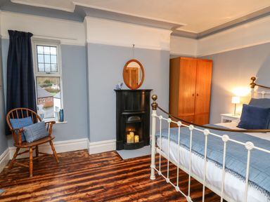 A bedroom with a bed a wooden chair a wardrobe and a small fireplace at Tirallen in Llangadog