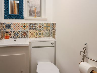 A bathroom with a toilet sink soap dispenser and colorful tiled backsplash at Tirallen in Llangadog