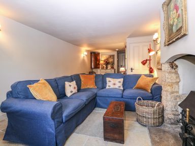 A living room with a blue sofa and a coffee table at Mallards in Bourton-On-The-Water