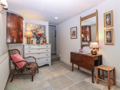 A hallway with a chest of drawers and a wall mirror at Mallards in Bourton-On-The-Water