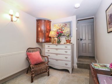 A hallway with a chair and dresser at Mallards in Bourton-On-The-Water