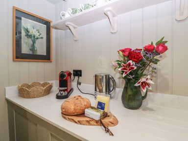 A kitchen with coffee machine and flower arrangement at Mallards in Bourton-On-The-Water