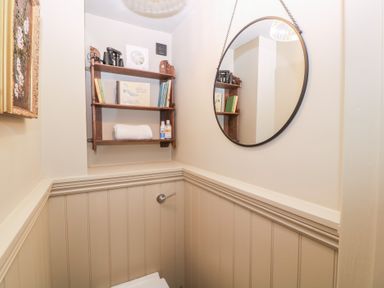 A bathroom with a toilet and shelves holding towels and toiletries at Mallards in Bourton-On-The-Water