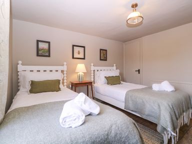 A bedroom with two single beds and paintings at Mallards in Bourton-On-The-Water