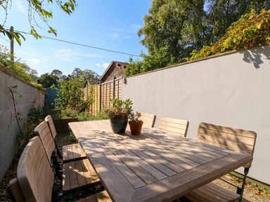 A garden with a wooden table and chairs at Mallards in Bourton-On-The-Water