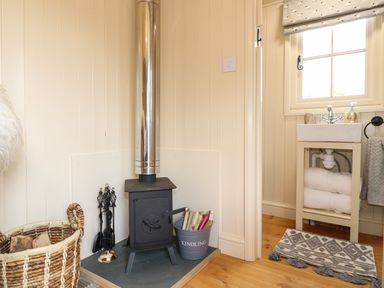 A corner with a wood burning stove next to a sink with towels at High Grounds Shepherd's Hut Boylestone near Ashbourne