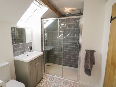 A bathroom with a glass shower enclosure a sink with a cabinet and a towel on a rail at The Old Piggery in Defford