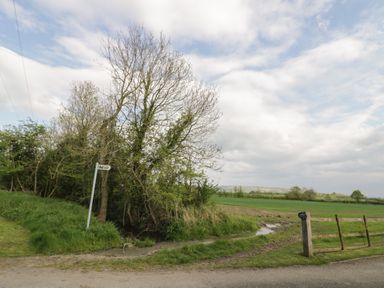 A rural landscape with trees a dirt path and a directional signpost at The Old Piggery in Defford