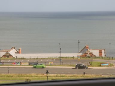A coastal view with parked cars facing the sea at Foxton Penthouse in Whitby